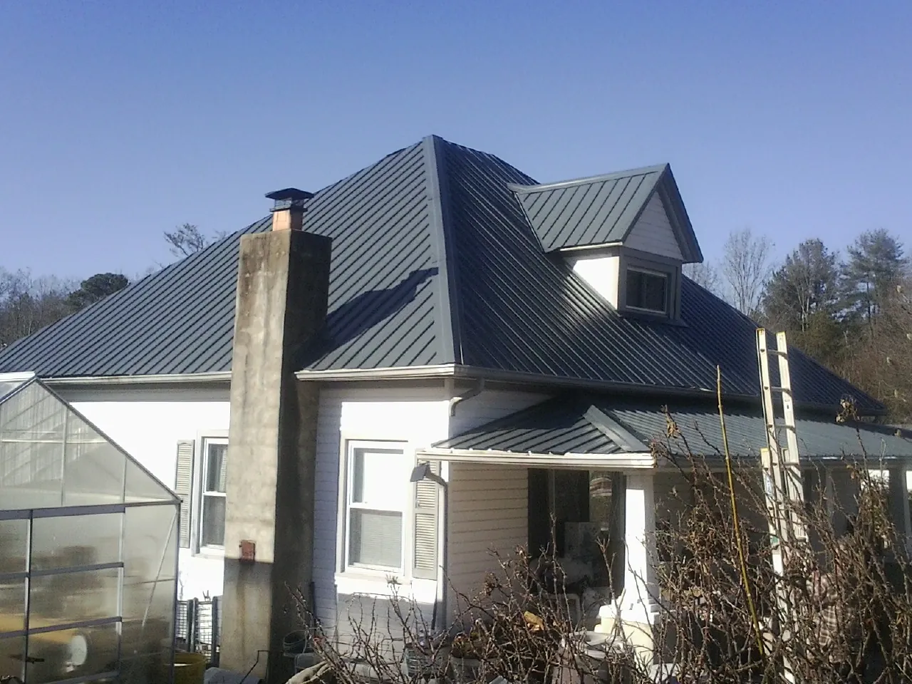Dark blue standing seam metal roof on a white farmhouse with dormer — Slate & Tile Roof Repair by Roofing Brothers in Rockmart