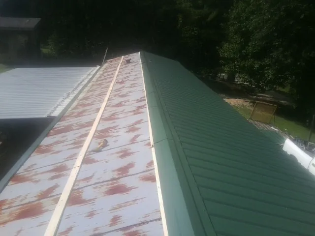 Old rusted panels beside newly installed green metal roofing — Wind Damage Roof Repair by Roofing Brothers in Rockmart