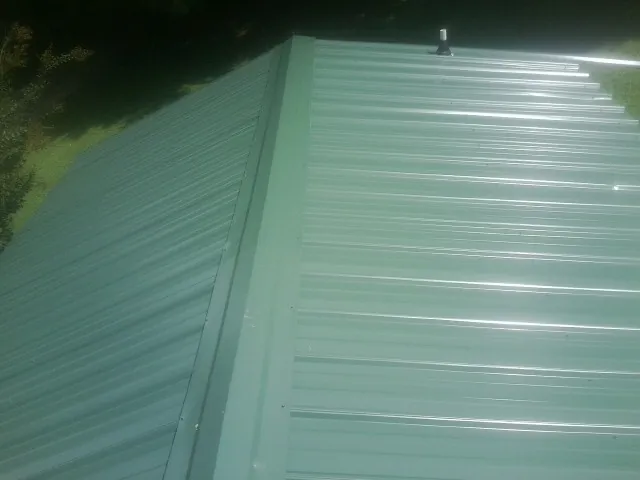 New green metal panels meeting at the ridge of a roof — Flat Roof Repair work by our crew in Rockmart