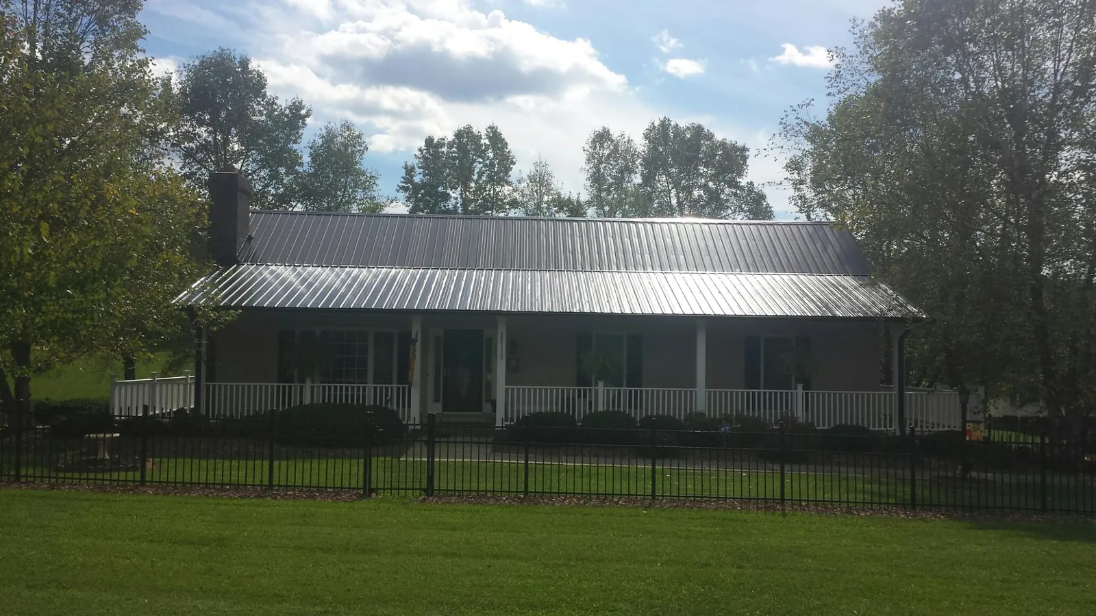 Gray metal roof on a brick ranch with a full width front porch — Gutter Guard Installation work by our crew in Rockmart