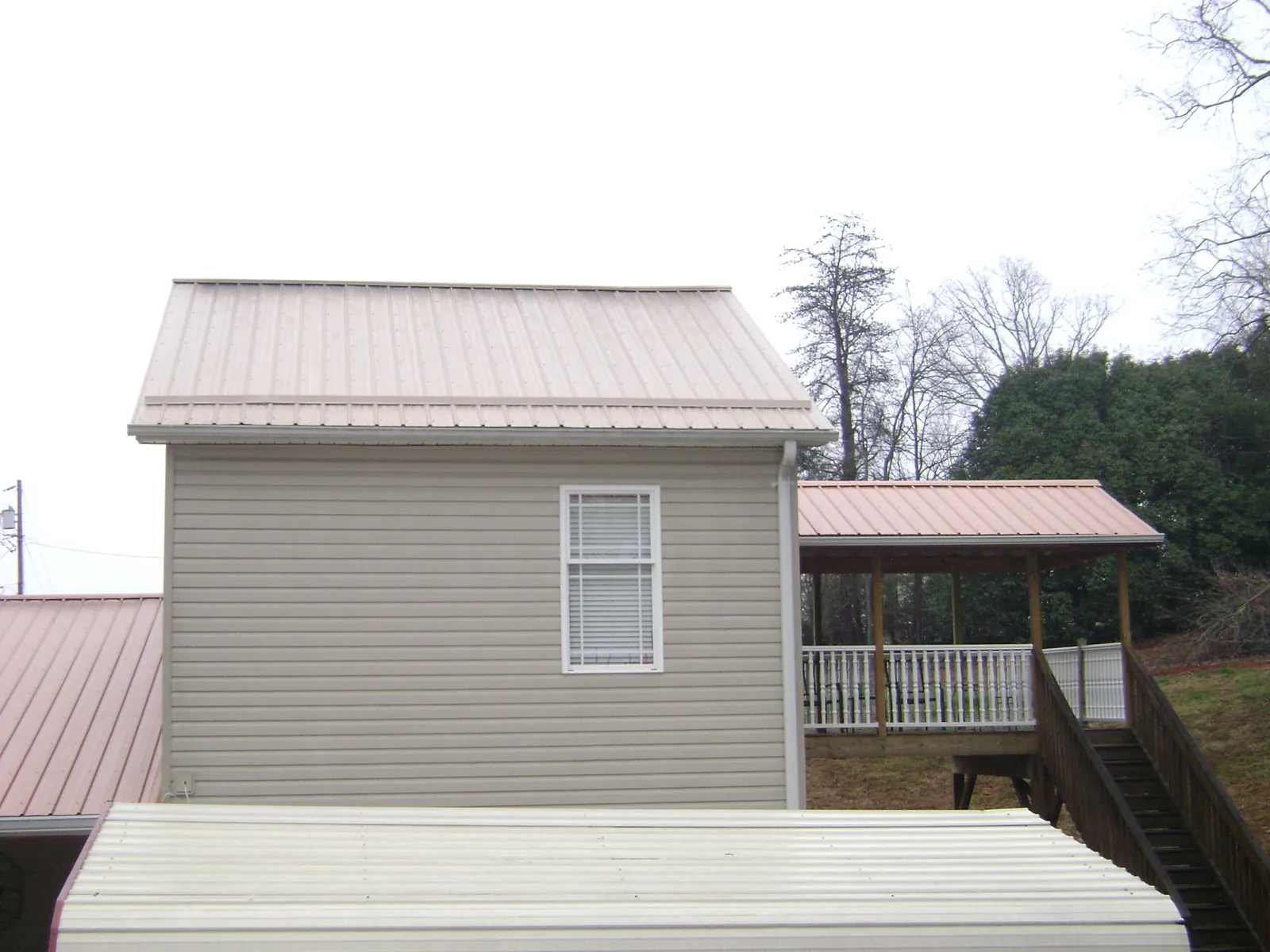 Tan metal roofs on a two story addition and attached porch, from a Roof Replacement job in Rockmart
